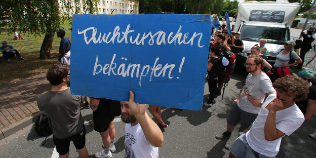 Demonstranten halten ein Schild hoch