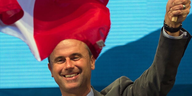 ein grinsender Mann unter einer Österreich-Fahne ein grinsender Mann unter einer Österreich-Fahne