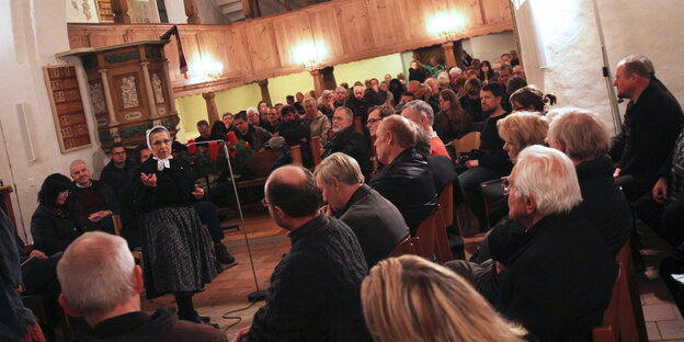 Menschen in einer Kirche. Eine Frau spricht