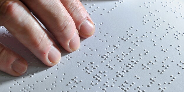 Eine Hand liest eine Seite in Brailleschrift Eine Hand liest eine Seite in Brailleschrift
