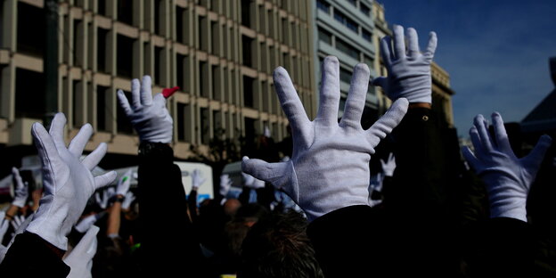 Hände in weißen Handschuhen und gespreizten Fingern sind in die Höhe gestreckt Hände in weißen Handschuhen und gespreizten Fingern sind in die Höhe gestreckt