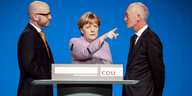 Angela Merkel hinter einem Rednerpult zeigt mit dem Finger in eine Richtung, rechts und links von ihr stehen Männer in Anzügen und sehen sie an