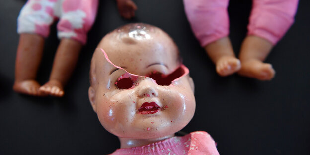 Rosa bekleidete Puppenfüsschen und ein zertrümmertes Puppengesich Rosa bekleidete Puppenfüsschen und ein zertrümmertes Puppengesich