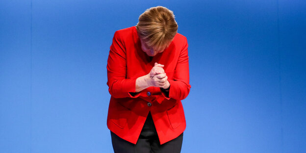 Angela Merkel schaut nach unten, ihre Hände sind gefaltet Angela Merkel schaut nach unten, ihre Hände sind gefaltet