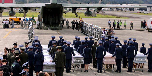 Soldaten und Polizisten begleiten die Särge zu einem Transportflugzeug. Soldaten und Polizisten begleiten die Särge zu einem Transportflugzeug.
