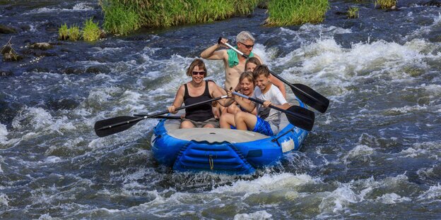 Eine Familie im Schlauchboot im Wildwasser Eine Familie im Schlauchboot im Wildwasser