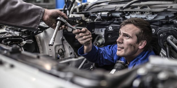 Ein Automechaniker guckt durch Autobauteile Ein Automechaniker guckt durch Autobauteile