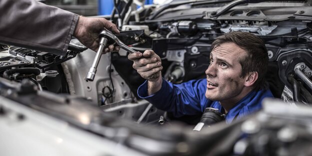 Ein Automechaniker guckt durch Autobauteile