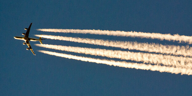 Hinter einem Flugzeug sind Kondensstreifen sichtbar