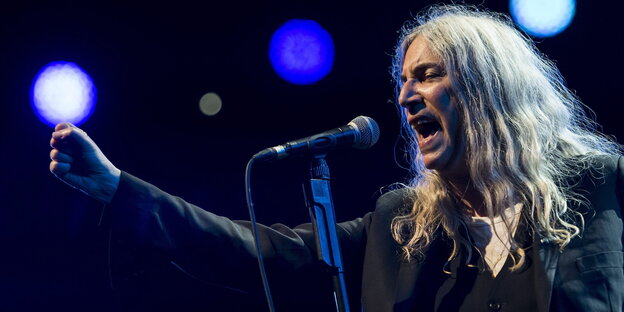 Patti Smith singt leidenschaftlich und streckt die Faust in die Luft Patti Smith singt leidenschaftlich und streckt die Faust in die Luft