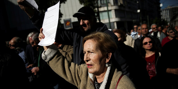 Menschen auf der Straße, eine Frau hält ein Blatt Papier in die Luft Menschen auf der Straße, eine Frau hält ein Blatt Papier in die Luft