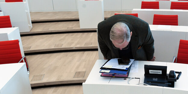 Alexander Gauland im brandenburgischen Landtag, sein Kopf liegt fast auf der Tischplatte