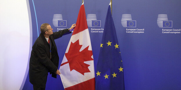 Ein EU-Mitarbeiter zupft die kanadische Flagge neben der EU-Flagge zurecht Ein EU-Mitarbeiter zupft die kanadische Flagge neben der EU-Flagge zurecht