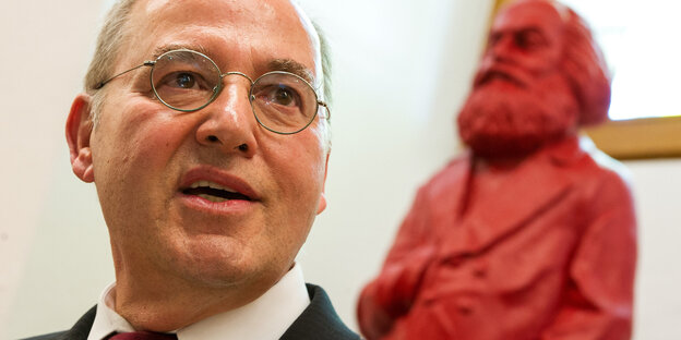 Ein Mann steht vor einer Karl-Marx-Figur Ein Mann steht vor einer Karl-Marx-Figur