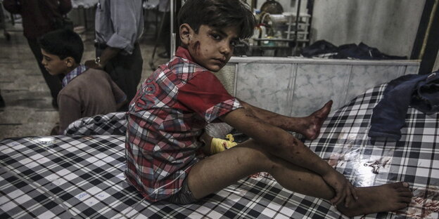 Ein blutverschmierter syrischer Junge sitzt auf einem Krankenhausbett Ein blutverschmierter syrischer Junge sitzt auf einem Krankenhausbett