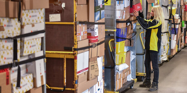 Eine Mitarbeiterin überprüft die Ladung an einem Transportwagen für Pakete im DHL-Paketzentrum in Rüdersdorf Eine Mitarbeiterin überprüft die Ladung an einem Transportwagen für Pakete im DHL-Paketzentrum in Rüdersdorf