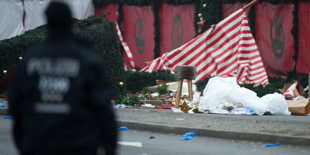 Ein Polizist vor zerstörten Weihnachtsbuden Ein Polizist vor zerstörten Weihnachtsbuden
