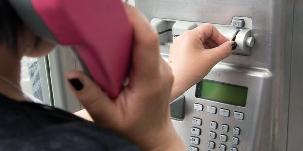 Eine Frau telefoniert in einer Telefonzelle Eine Frau telefoniert in einer Telefonzelle
