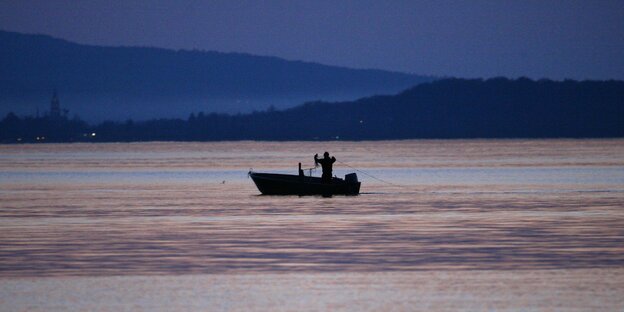 Ein Fischer auf einem Boot im letzten Licht des Tages Ein Fischer auf einem Boot im letzten Licht des Tages