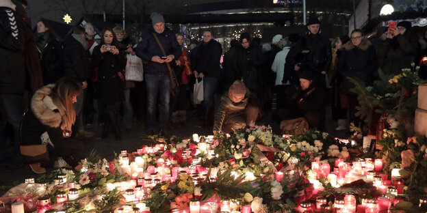Menschen stellen Kerzen auf einem Platz ab Menschen stellen Kerzen auf einem Platz ab