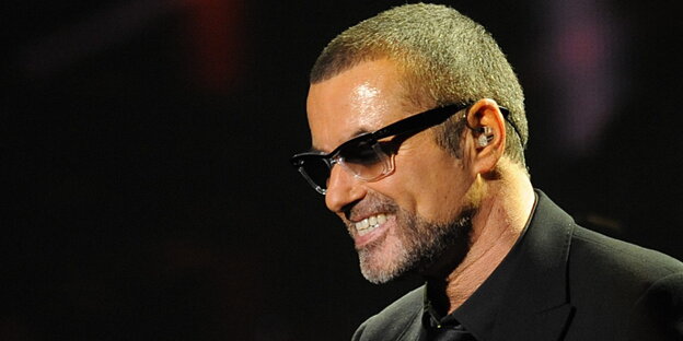 George Michael im schwarzen Anzug, mit schwarzer Sonnenbrille, vor schwarzem Hintergrund George Michael im schwarzen Anzug, mit schwarzer Sonnenbrille, vor schwarzem Hintergrund