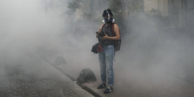 Eine türkische Journalistin steht mit Kamera und Rauchmaske in einer Nebelwolke Eine türkische Journalistin steht mit Kamera und Rauchmaske in einer Nebelwolke