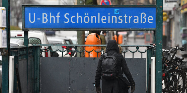 Eine Frau in schwarzer Jacke geht die Treppe zum U-Bahnhof Schönleinstraße hinunter Eine Frau in schwarzer Jacke geht die Treppe zum U-Bahnhof Schönleinstraße hinunter