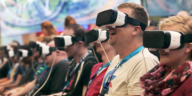 Menschen sitzen in einer Reihe und tragen VR-Brillen Menschen sitzen in einer Reihe und tragen VR-Brillen