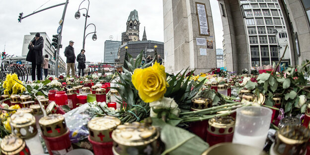 Passanten stehen in Berlin vor einem Blumen- und Kerzenmeer am Breitscheidplatz Passanten stehen in Berlin vor einem Blumen- und Kerzenmeer am Breitscheidplatz
