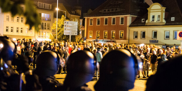Behelmte Polizisten stehen vor einer großen Menschengruppe Behelmte Polizisten stehen vor einer großen Menschengruppe
