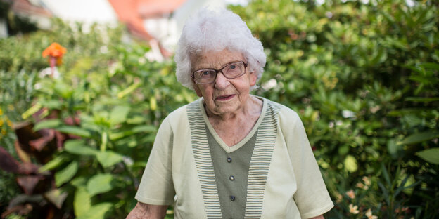 Eine ältere Dame steht in einem Garten Eine ältere Dame steht in einem Garten