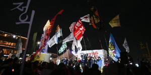 Eine Gruppe von Menschen weht mit Fahnen. Sie demonstrieren in Seoul gegen die Südkoreanische Präsidentin Park Geun-hye.