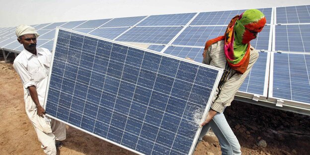Zwei Männer tragen ein Solarpanel Zwei Männer tragen ein Solarpanel