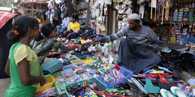 Ein Mann in einem kleinen Laden in Myanmar verkauft zwei Mädchen etwas Ein Mann in einem kleinen Laden in Myanmar verkauft zwei Mädchen etwas