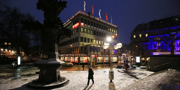 Ein Mensch läuft bei Nacht über einen verschneiten, einsamen Platz Ein Mensch läuft bei Nacht über einen verschneiten, einsamen Platz