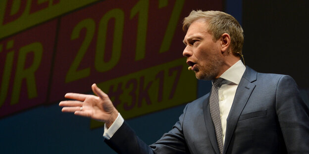 Ein Mann sagt etwas und zeigt mit der Hand in eine Richtung Ein Mann sagt etwas und zeigt mit der Hand in eine Richtung