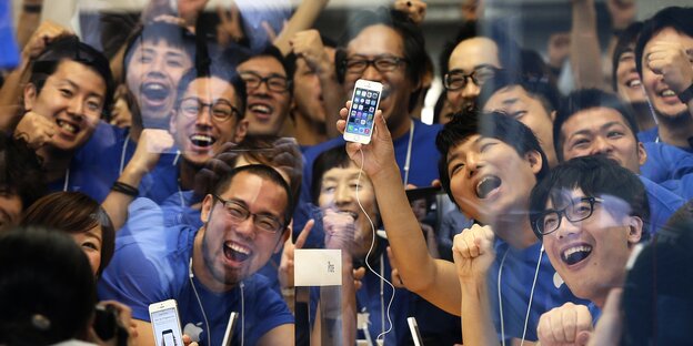 Mitarbeiter*innen eines Apple Stores in Tokio posieren mit dem Apple 5S Mitarbeiter*innen eines Apple Stores in Tokio posieren mit dem Apple 5S