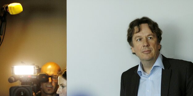 Jörg Kachelmann vor einer weißen Wand, links daneben ein Fotograf mit Blitzlicht Jörg Kachelmann vor einer weißen Wand, links daneben ein Fotograf mit Blitzlicht