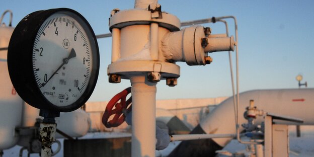 Ein Manometer neben weißen Metallrohren Ein Manometer neben weißen Metallrohren