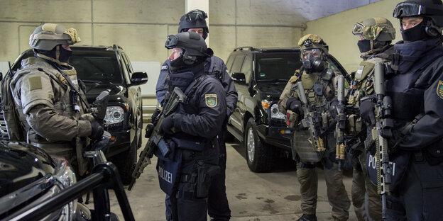 Polizisten mit neuen Waffen vor neuen gepanzerten Fahrzeugen Polizisten mit neuen Waffen vor neuen gepanzerten Fahrzeugen