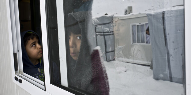 Kinder stehen an einem Fenster Kinder stehen an einem Fenster