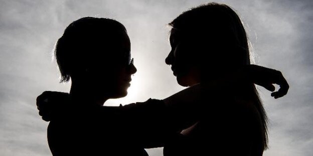 zwei Frauen umarmen sich, erkennbar sind sie vor dem Gegenlicht aber nur in Umrissen zwei Frauen umarmen sich, erkennbar sind sie vor dem Gegenlicht aber nur in Umrissen
