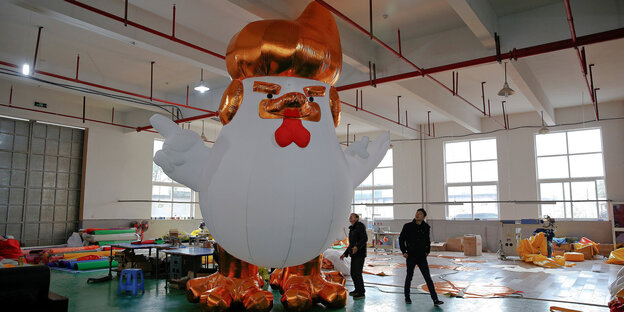 Ein großes aufblasbares Huhn, das Ähnlichkeiten mit Donald Trump hat, steht in einer Halle Ein großes aufblasbares Huhn, das Ähnlichkeiten mit Donald Trump hat, steht in einer Halle