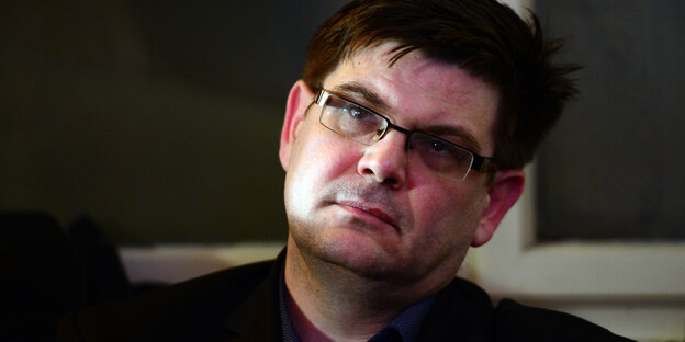 Ein Mann mit Brille hält den Kopf schräg und guckt ernst Ein Mann mit Brille hält den Kopf schräg und guckt ernst