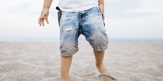 Ein Kind spielt in einer Jeans am Strand Ein Kind spielt in einer Jeans am Strand