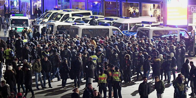 eine Menschenmenge und Polizisten, im Hintergrund Polizeifahrzeuge eine Menschenmenge und Polizisten, im Hintergrund Polizeifahrzeuge