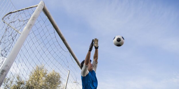 Torwart springt vor dem Tor einem anfliegendem Ball entgegen Torwart springt vor dem Tor einem anfliegendem Ball entgegen
