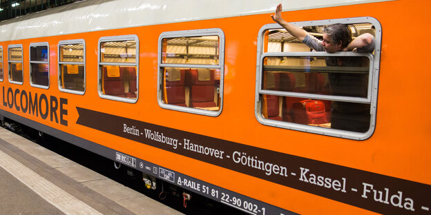 Ein orangener Zug am Gleis Ein orangener Zug am Gleis