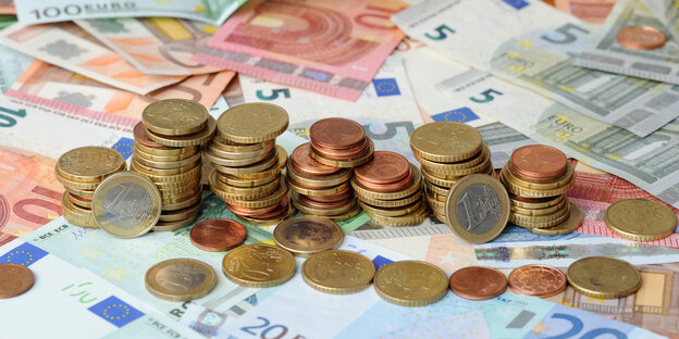 Euromünzen liegen in Stapeln auf Euroscheinen Euromünzen liegen in Stapeln auf Euroscheinen