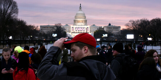Ein Mann mit einer roten Schirmmütze steht vor dem Capitol-Gebäude in Washington D.C. Ein Mann mit einer roten Schirmmütze steht vor dem Capitol-Gebäude in Washington D.C.